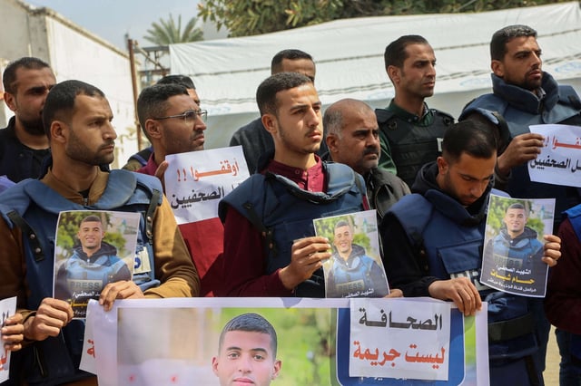 Palestinian journalists lift placards during a rally in protest of the killing of fellow reporters Hussam Shabat and Muhammad Mansour in Israeli strikes a day earlier, at the al-Ahli Arab hospital, also known as the Baptist hospital, in Gaza City on March 25, 2025.