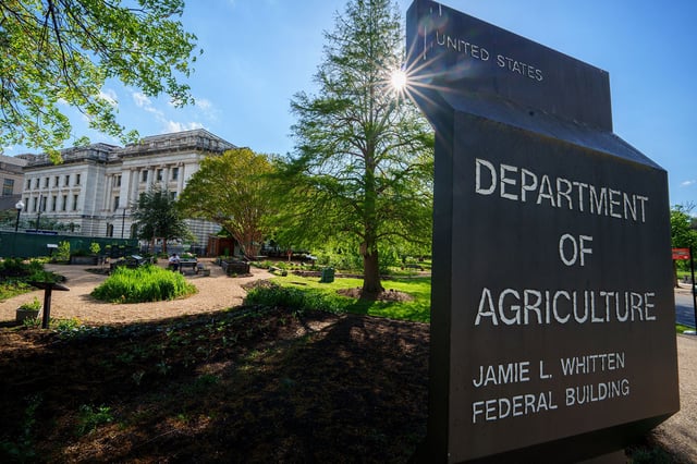 The sun flares behind the sign marking the headquarters building for the US Department of Agriculture on April 18, 2024, in Washington, DC.