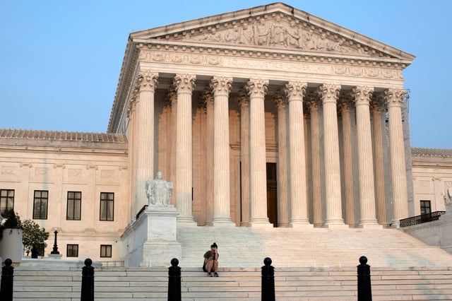 A woman sits on the steps of the U.S. Supreme Court in Washington, U.S., August 14, 2024.