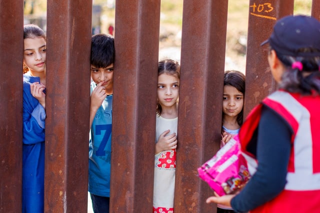 Children from Afghanistan wait for some candy from an air worker after migrants gathered between the primary and secondary border fences between Mexico and the United States as they await processing by U.S immigration in San Diego, U.S., September 12, 2023.  REUTERS/Mike Blake/File Photo