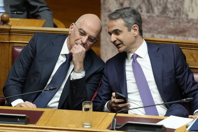 Greece's Prime Minister Kyriakos Mitsotakis, right, speaks with Defense Minister Nikos Dendias, during a presentation of military spending plans, at the Greek Parliament, in Athens, Wednesday, April 2, 2025. (AP Photo/Petros Giannakouris)