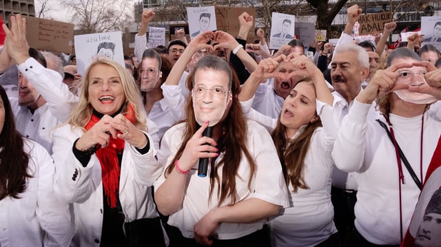 Weiss gekleidete Menschen mit Imamoglu Maske protestieren gutgelaunt