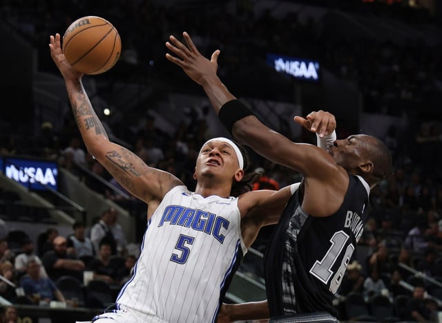 Orlando Magic forward Paolo Banchero (5) takes a contested shot against San Antonio Spurs center Bismack Biyombo (18) during the first half of an NBA basketball game in San Antonio, Tuesday, April 1, 2025. (AP Photo/Kin Man Hui)