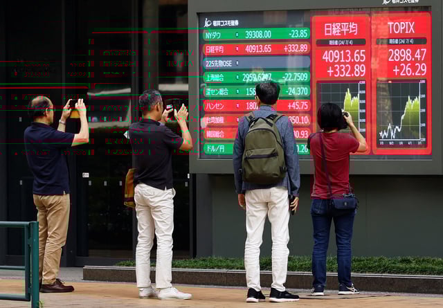 People take pictures of a monitor displaying Topix share average and Nikkei share average outside a brokerage in Tokyo, Japan, July 4, 2024. REUTERS/Kim Kyung-Hoon/File Photo