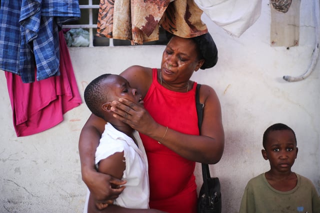 A child is helped by his mother after being affected by tear gas used by police officers during a protest against insecurity, at a shelter for displaced people in the Bourdon neighborhood, in Port-au-Prince, Haiti April 2, 2025. REUTERS/Jean Feguens Regala