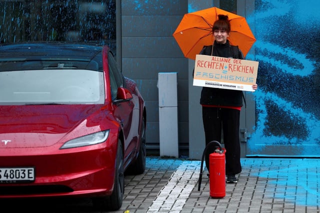 Une manifestante proteste devant une concession Tesla de Berlin contre les positions politiques d'Elon Musk.

