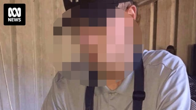 A young man wearing a baseball cap looks down at his phone
