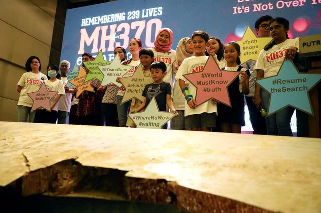 Family members of the victims pose for a group picture with a debris of the missing Malaysia Airlines flight MH370 during its sixth annual remembrance event in Putrajaya, Malaysia, March 7, 2020. REUTERS/Lim Huey Teng/File Photo