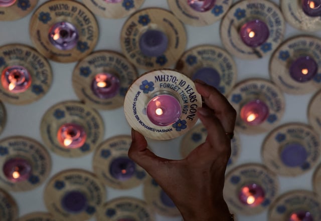 A family member of the missing Malaysia Airlines flight MH370 steward Mohd Hazrin Mohamed Hasnan, holds a candle bearing his name during a remembrance event marking the 10th anniversary of its disappearance, in Subang Jaya, Malaysia March 3, 2024. REUTERS/Hasnoor Hussain/File Photo