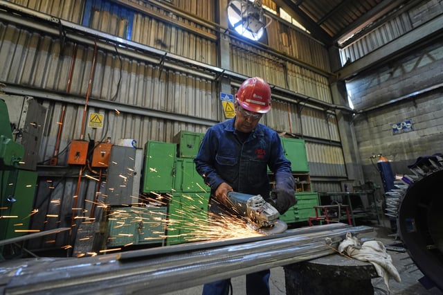A worker sands metal at a plant that produces parts for large electric vehicles in Mexico City, Wednesday, April 2, 2025. (AP Photo/Fernando Llano)
