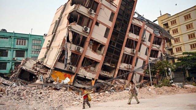 Children walk past a collapsed building in Mandalay