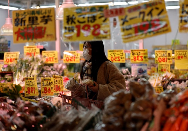 A shopper is reflected on a mirror glass as she checks food items at a supermarket in Tokyo, Japan January 20, 2023. REUTERS/Issei Kato/File Photo