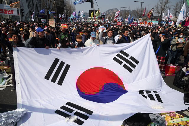 People hold up a South Korean flag as they celebrate after President Yoon Suk Yeol's impeachment was accepted, near the Constitutional Court in Seoul, South Korea, April 4, 2025.   REUTERS/Kim Hong-ji