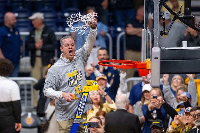 Chattanooga head coach Dan Earl cuts down a piece of the net after the championship game.