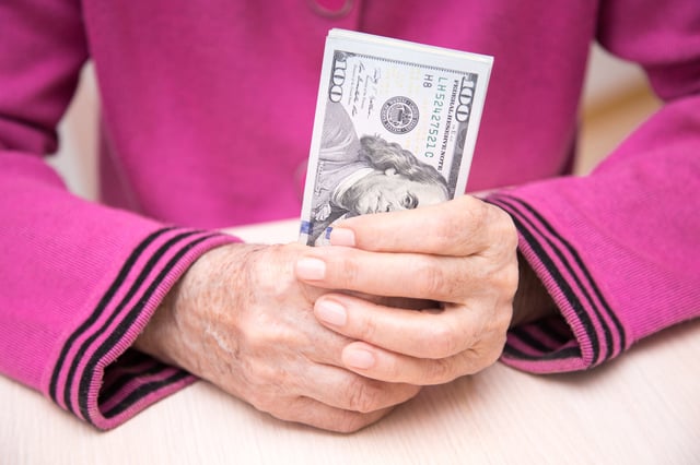 Stock image/file photo: An elderly person holding U.S. Dollar bills.