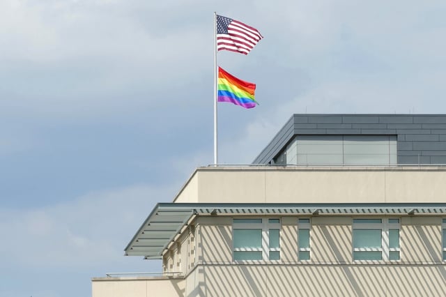 Eine Regenbogenfahne und eine US-Flagge wehen auf einem Dach.