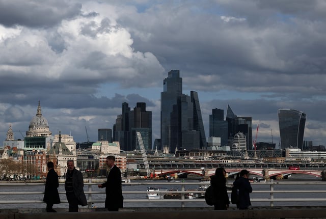 People walk across Waterloo Bridge with skyscrapers of the City of London financial district and St Paul’s Cathedral seen behind, in London, Britain, March 28, 2025. REUTERS/Toby Melville/File Photo