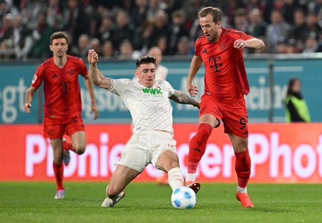 Soccer Football - Bundesliga - FC Augsburg v Bayern Munich - WWK Arena, Augsburg, Germany - April 4, 2025 Bayern Munich's Harry Kane in action with FC Augsburg's Cedric Zesiger REUTERS/Angelika Warmuth