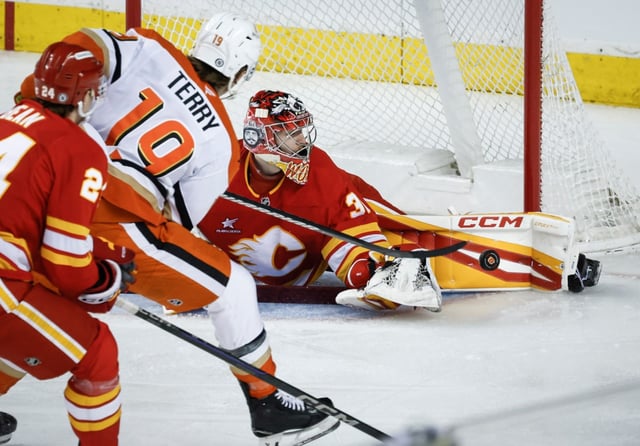 The Ducks’ Troy Terry, left, has his shot kicked away by Flames goalie Dustin Wolf during the third period Thursday, April 3, 2025, in Calgary. (Jeff McIntosh/The Canadian Press via AP)