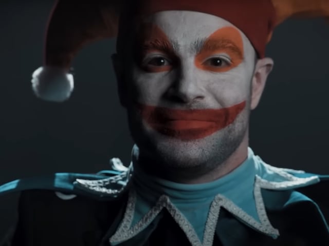 The jester from Balatro, portrayed in unsettling detail in real life, wears an uncanny smile and stares at the viewer.