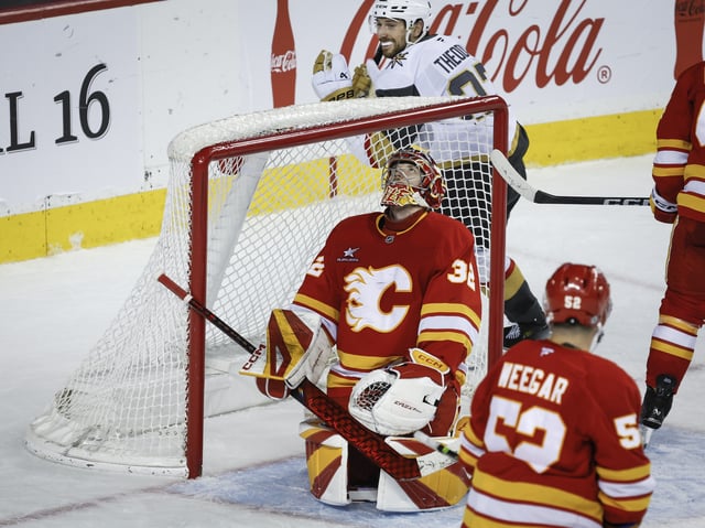 Vegas Golden Knights' Shea Theodore, top, celebrates his team's winning goal as Calgary Flames goalie Dustin Wolf reacts during overtime  NHL hockey action in Calgary on Saturday, April 5, 2025.