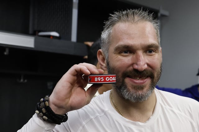 Apr 6, 2025; Elmont, New York, USA;  Washington Capitals left wing Alex Ovechkin (8) poses with the puck as he celebrates after scoring a goal in the 2nd period against the New York Islanders at UBS Arena. Geoff Burke-Imagn Images
