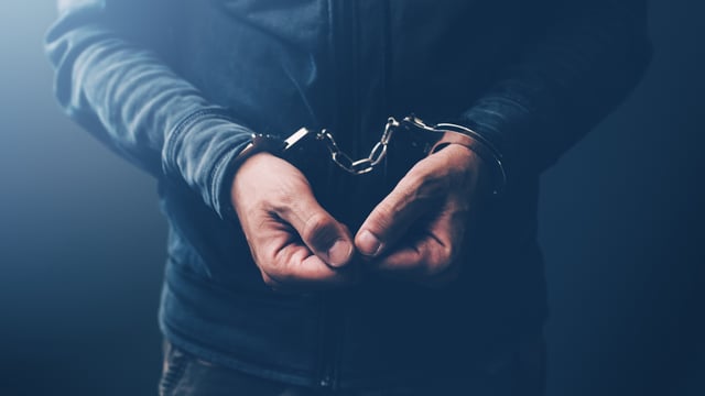 Arrested computer hacker and cyber criminal with handcuffs, close up of hands. (iStockphoto)