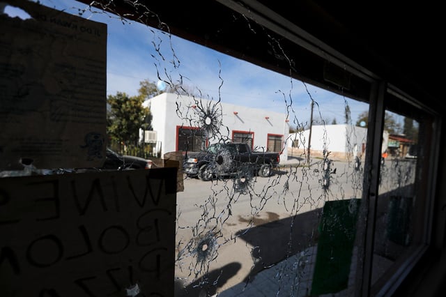 A shop's windows are riddled with bullets near City Hall after a gun battle between a heavily armed drug cartel assault group and security forces in Villa Union, Mexico, near the border with the US, in December 2019.