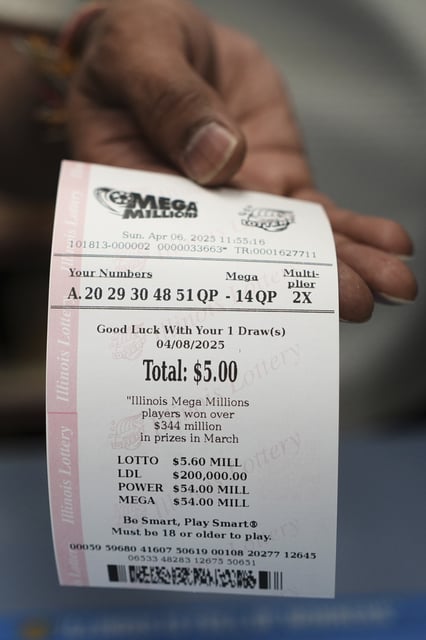 An employee of Mares Mart hands a Mega Millions lottery ticket to a customer in Chicago, Sunday, April 6, 2025. (AP Photo/Nam Y. Huh)