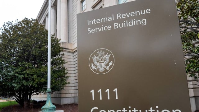 A sign outside the IRS headquarters displays the words "Internal Revenue Service Building" and the street address "1111 Constitution Ave."