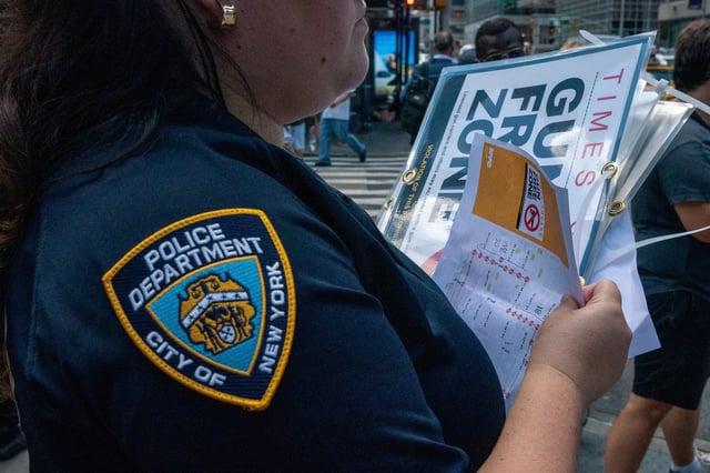 A New York City police officer holds a sign that reads "gun free zone" at Times Square as new gun laws are due to come into effect, in New York, U.S., August 31, 2022. REUTERS/David 'Dee' Delgado/File Photo