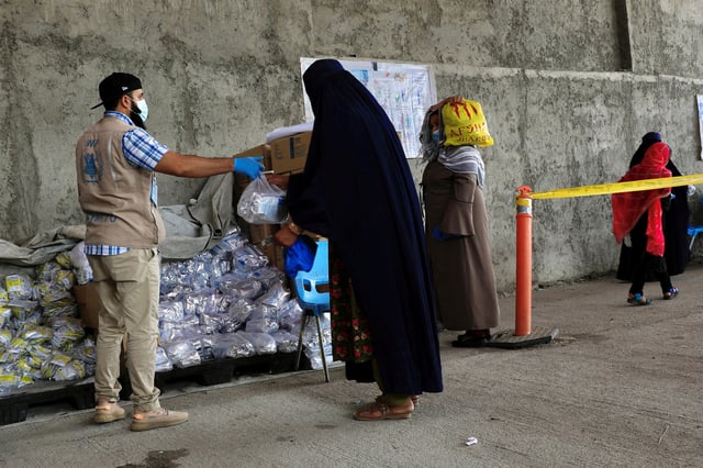 An Afghan woman receives food items for her children at a World Food Program (WFP) distribution centre in Kabul, Afghanistan, August 21, 2024. REUTERS/Sayed Hassib/File Photo