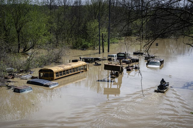 Community members steer a boat past flooded vehicles, Monday, April 7, 2025, in Frankfort, Ky. (AP Photo/Jon Cherry)