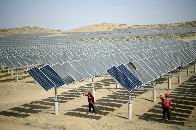 In einem Photovoltaik-Kraftwerk in Yinchuan, China, stauben Mitarbeiter nach windigem Wetter Photovoltaik-Paneele ab