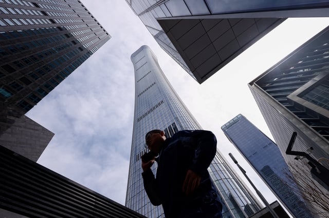 A man walks past buildings at Central Business District (CBD) in Beijing, China April 8, 2025. REUTERS/Tingshu Wang/File photo