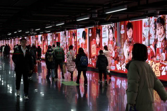 People walk in front of billlboards in a metro station in Shanghai, China, January 16, 2025.  REUTERS/Go Nakamura/File Photo