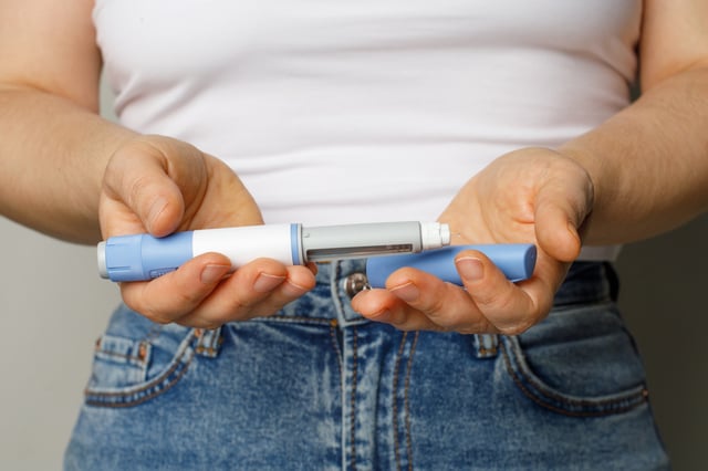 Stock image of a woman holding a semaglutide injector.