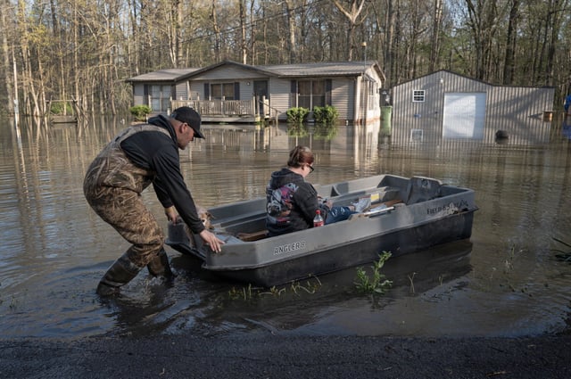 Dusty Baggett uses a boat to push his wife Rachel through floodwater to their home on April 7, 2025 in Paducah, Ky.