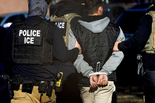 In this February 5 photo, Immigration and Customs Enforcement agents detain a man after conducting a raid at the Cedar Run apartment complex in Denver, Colorado.