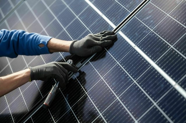Ein Mann montiert Photovoltaikmodule auf einem Dach