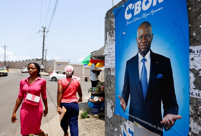 People walk next to a poster showing Brice Clotaire Oligui Nguema, presidential candidate and Gabonese junta leader, ahead of the 2025 Gabonese presidential election in Libreville, Gabon April 7, 2025. REUTERS/Luc Gnago/File Photo