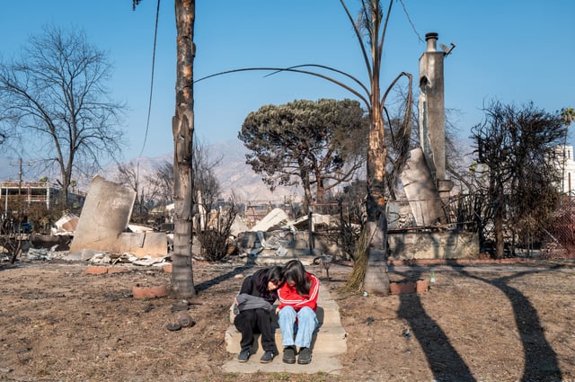 Sisters Emilee and Natalee De Santiago sit together on the front porch of what remains of their home on January 19, 2025, in Altadena, California.