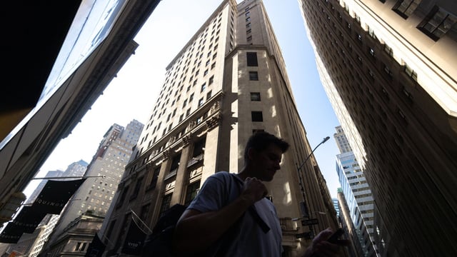Pedestrians walk along Wall Street near the New York Stock Exchange (NYSE) in New York, US.