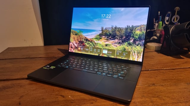 The Asus ROG Zephyrus G16 2025 gaming laptop on a wooden desk with the Windows 11 login screen on display