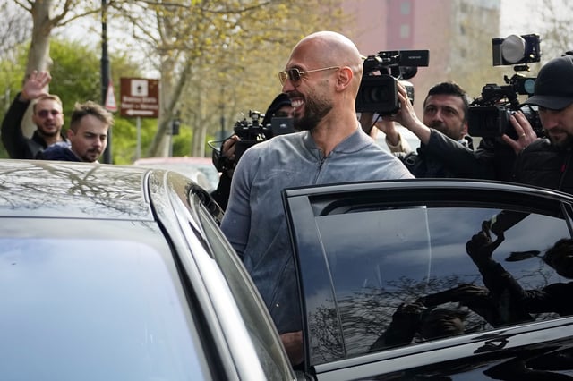 Andrew Tate smiles as he boards a car outside the Directorate for Investigating Organized Crime and Terrorism (DIICOT), in Bucharest, Romania, Tuesday, April 1, 2025. (AP Photo/Andreea Alexandru)