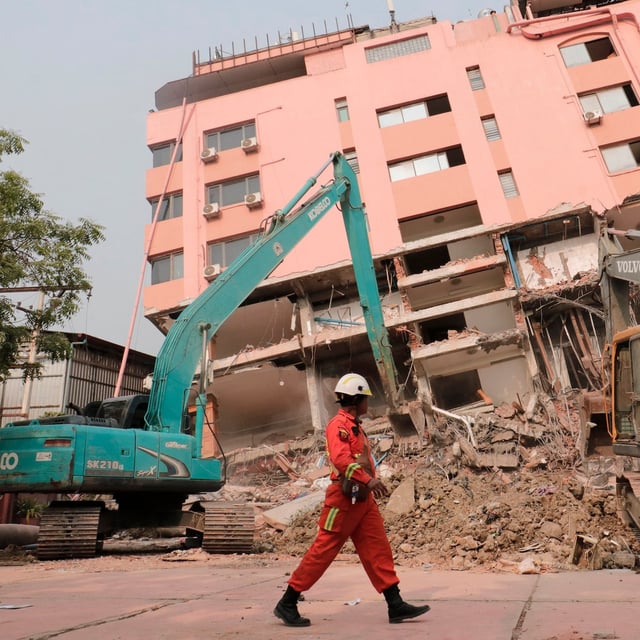TOPSHOT - A rescue worker walks past heavy construction equipment being used to clear rubble at the site of a collapsed building in Mandalay on April 5, 2025, following the March 28 earthquake. The shallow 7.7-magnitude earthquake on March 28 flattened buildings across Myanmar, killing more than 3,000 people and making thousands more homeless. (Photo by Zaw Htun / AFP) (Photo by ZAW HTUN/AFP via Getty Images)