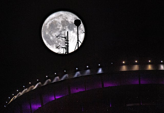 The full sturgeon supermoon rises behind antennas atop the Tower of the Americas in downtown San Antonio on Aug. 1, 2023. 