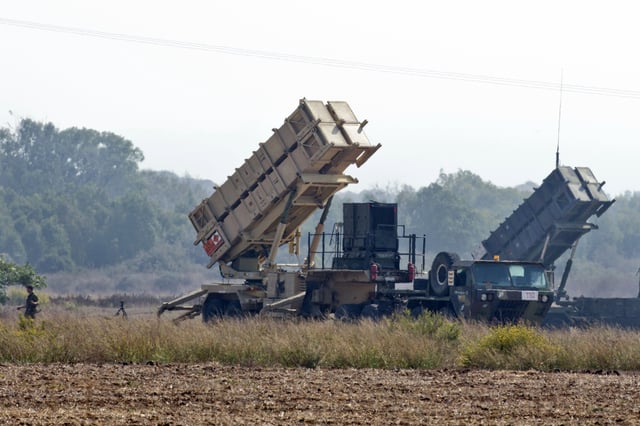 An Israli soldier walks nearby two patriot missile batteries, deployed on a field close to Atlit, on the outskirts of Haifa, on October 22, 2012. Israeli and US troops hold a vast missile defence exercise called Austere Challenge 12, in what was hailed as their largest-ever joint military operation.