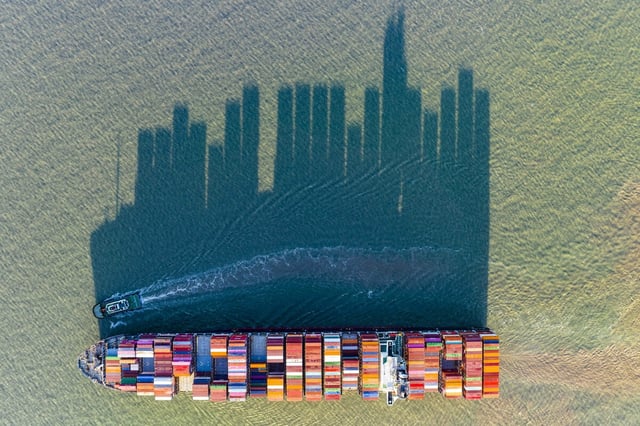 Ein sehr großes, mit Containern beladenes Containerschiff wirft einen riesigen Schatten