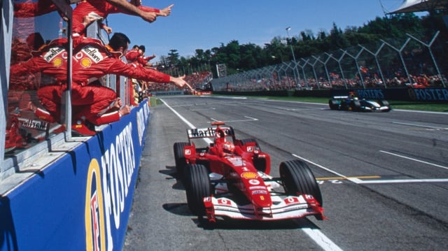 Ferrari team members salute Michael Schumacher as he wins in San Marino with the F2004 V10